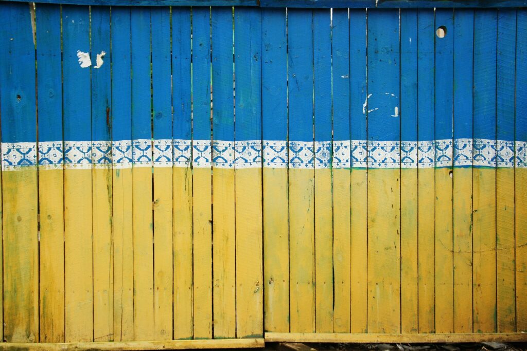 Fence painted in colors of Ukraine - photo by Tina Hartung on Unsplash.